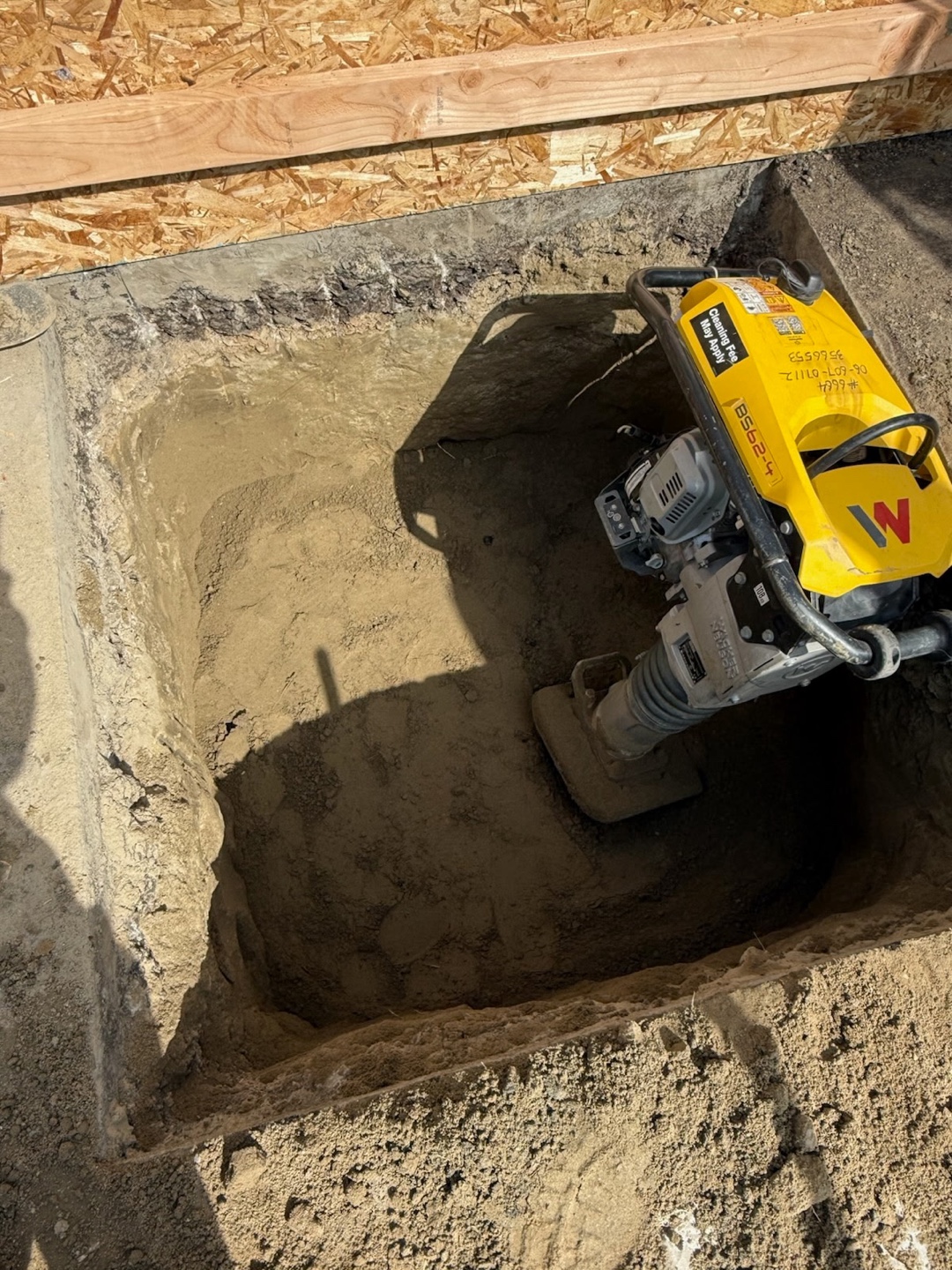 Open trench with plate compactor before backfill